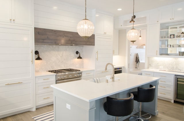 A white kitchen with white wooden drawers and round ceiling lights